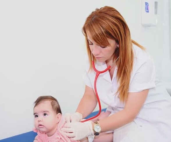 Dr. Günay Hacızadə körpəni stetoskopla müayinə edir